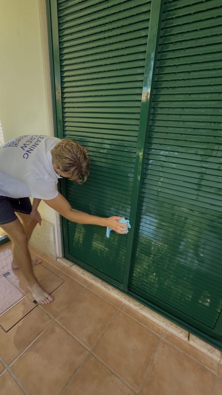 Cleaning glass beside a louvred shutter at an apartment in Vilamoura
