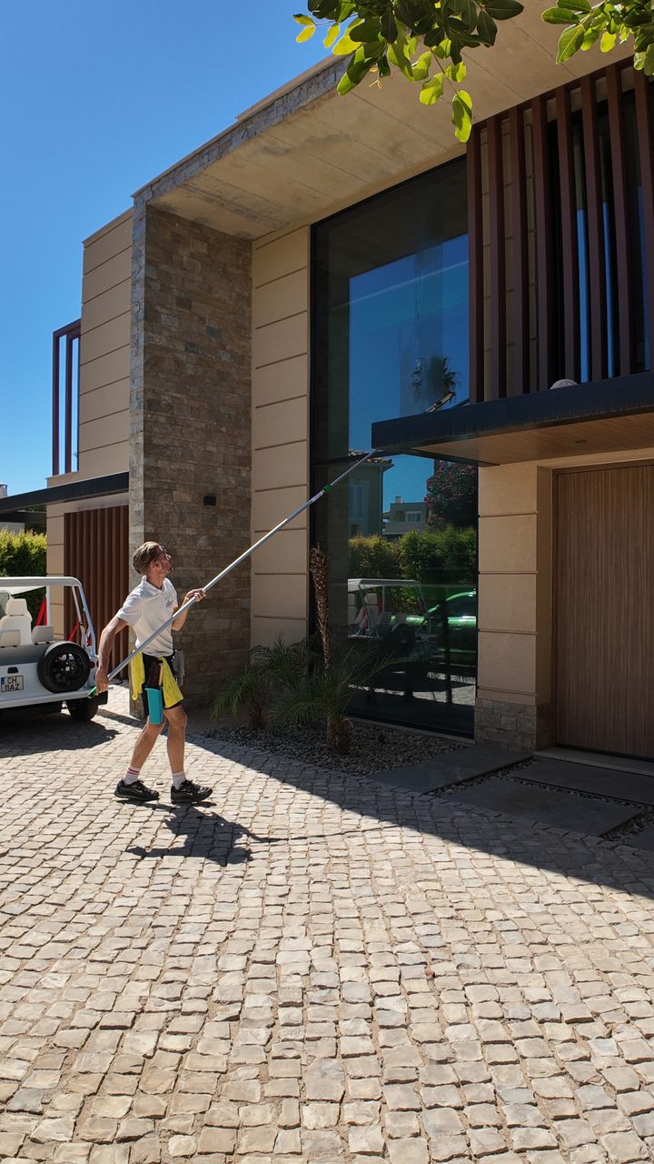 Pole cleaning the upper glass at a modern villa in the Golden Triangle