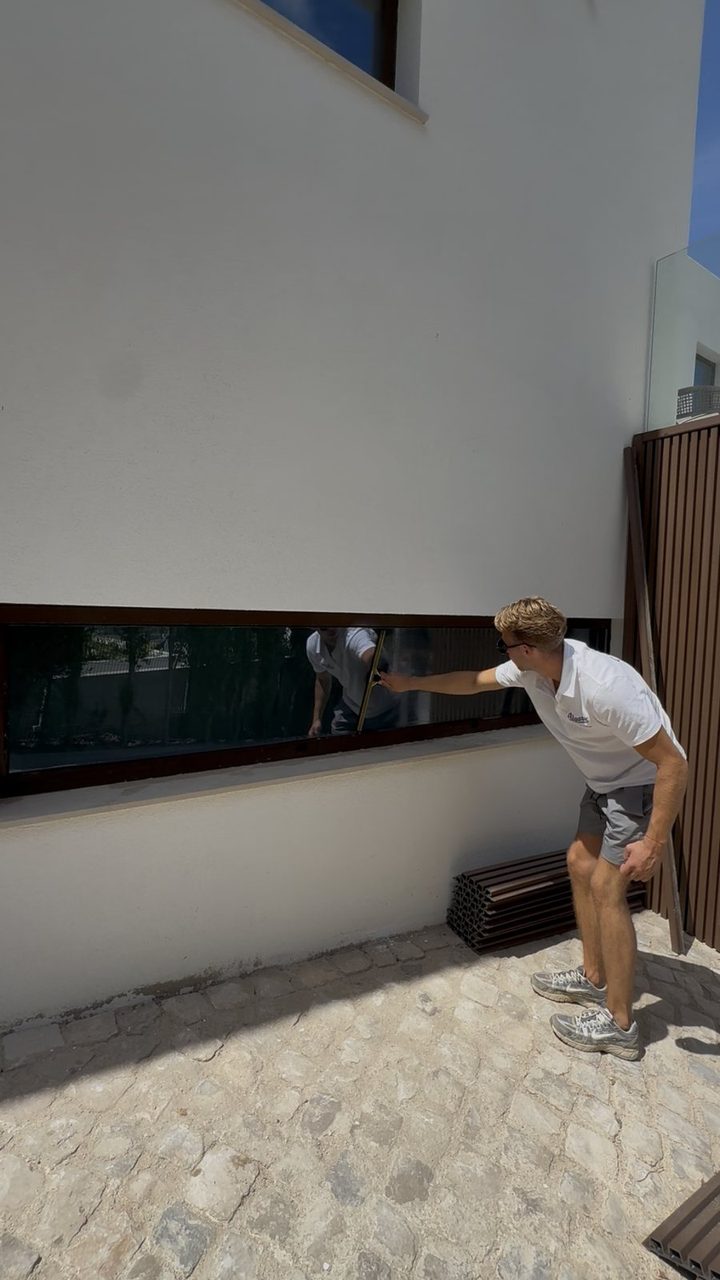 Cleaning a long ribbon window at a villa in Vale do Lobo