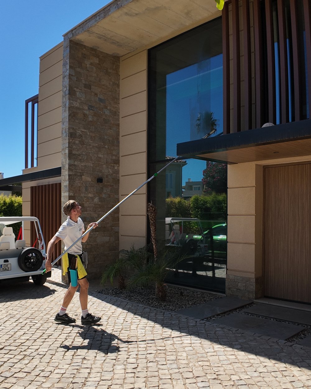 Algarve Cleaning Crew pole cleaning the upper glass on a villa