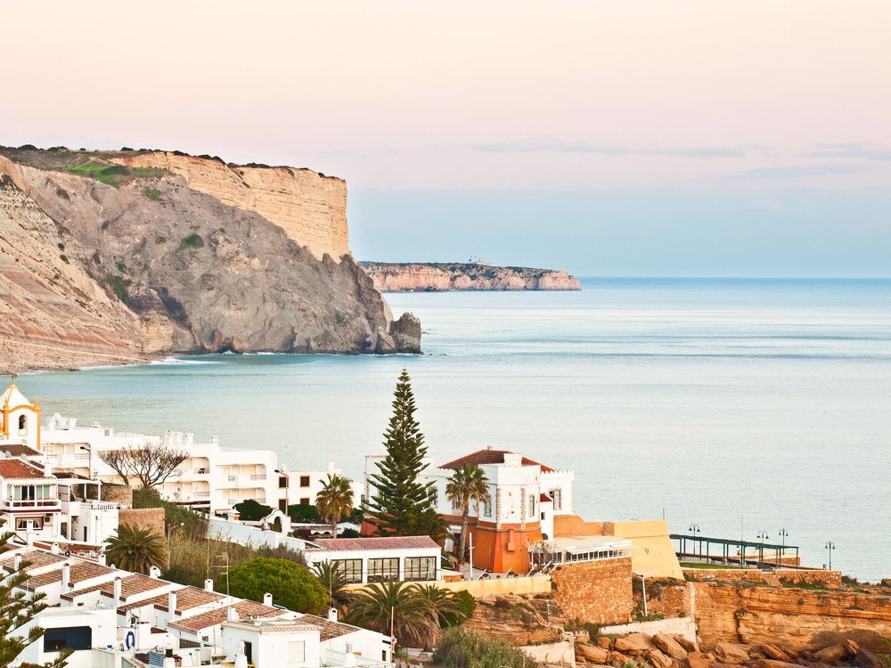 Whitewashed village of Luz below the Rocha Negra cliff, Algarve