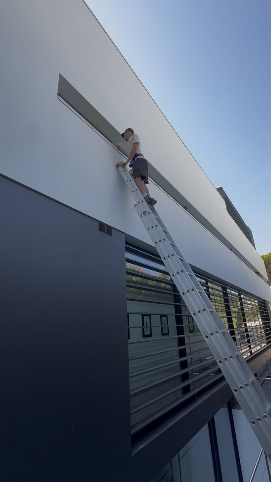 Cleaning high exterior glass from the top of a ladder at a Vale do Lobo villa