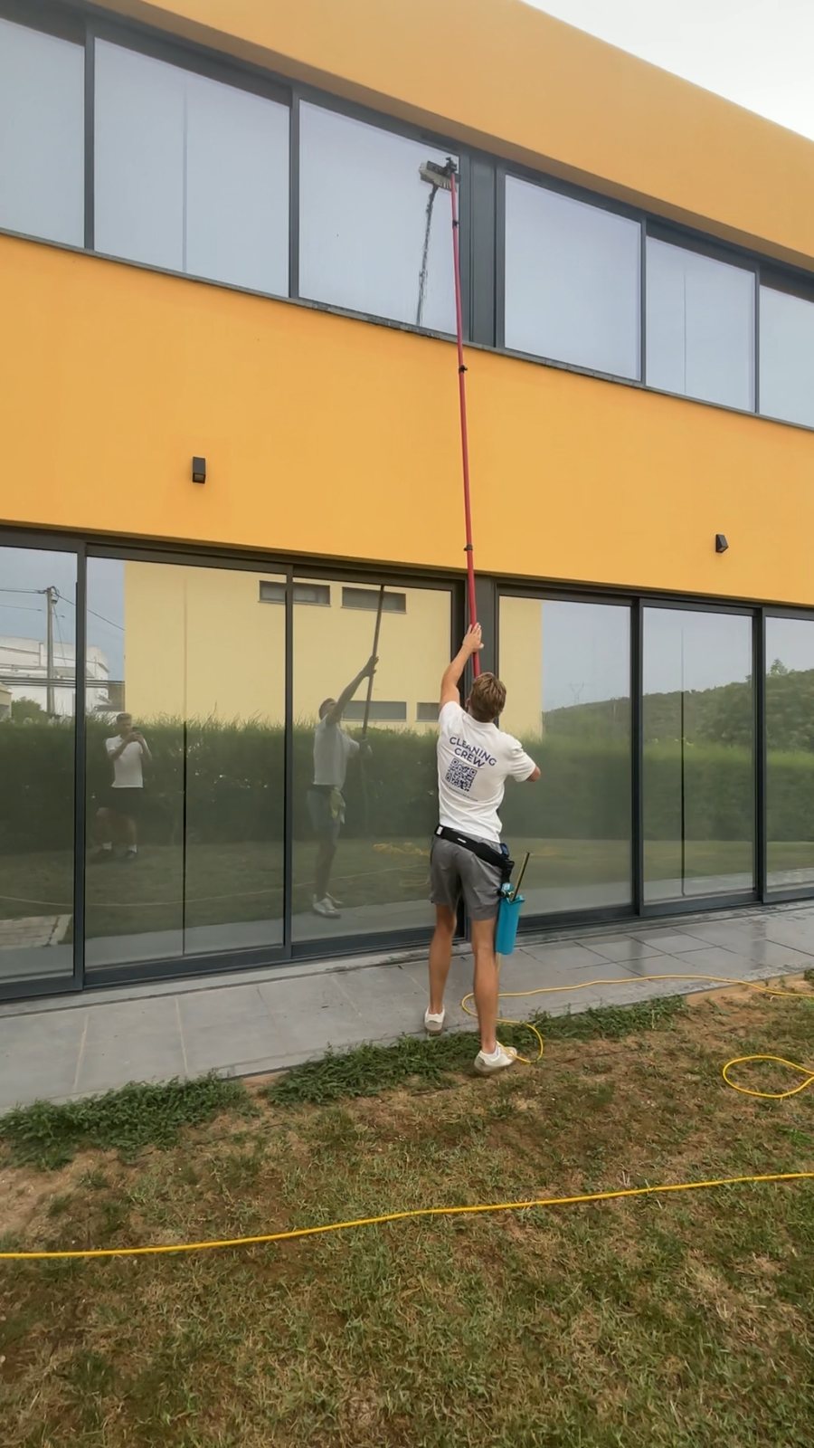 Cleaning upper-floor windows with a long pole at a villa in Praia da Luz