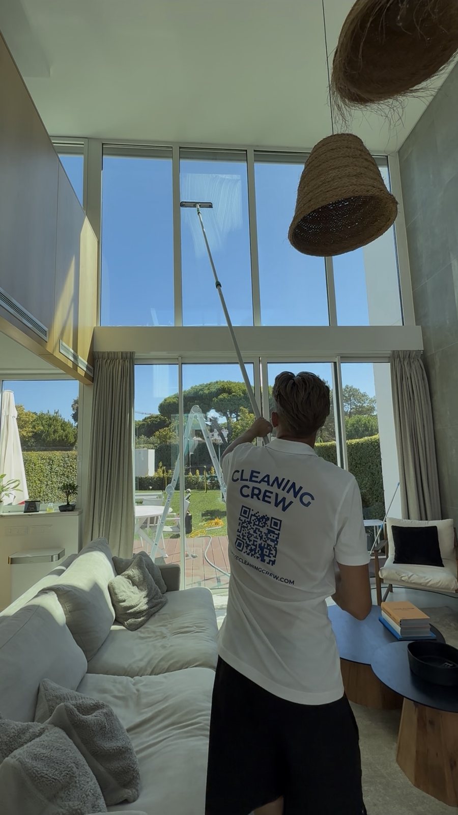 Cleaning double-height living room glass with a pole at a villa in Lagos
