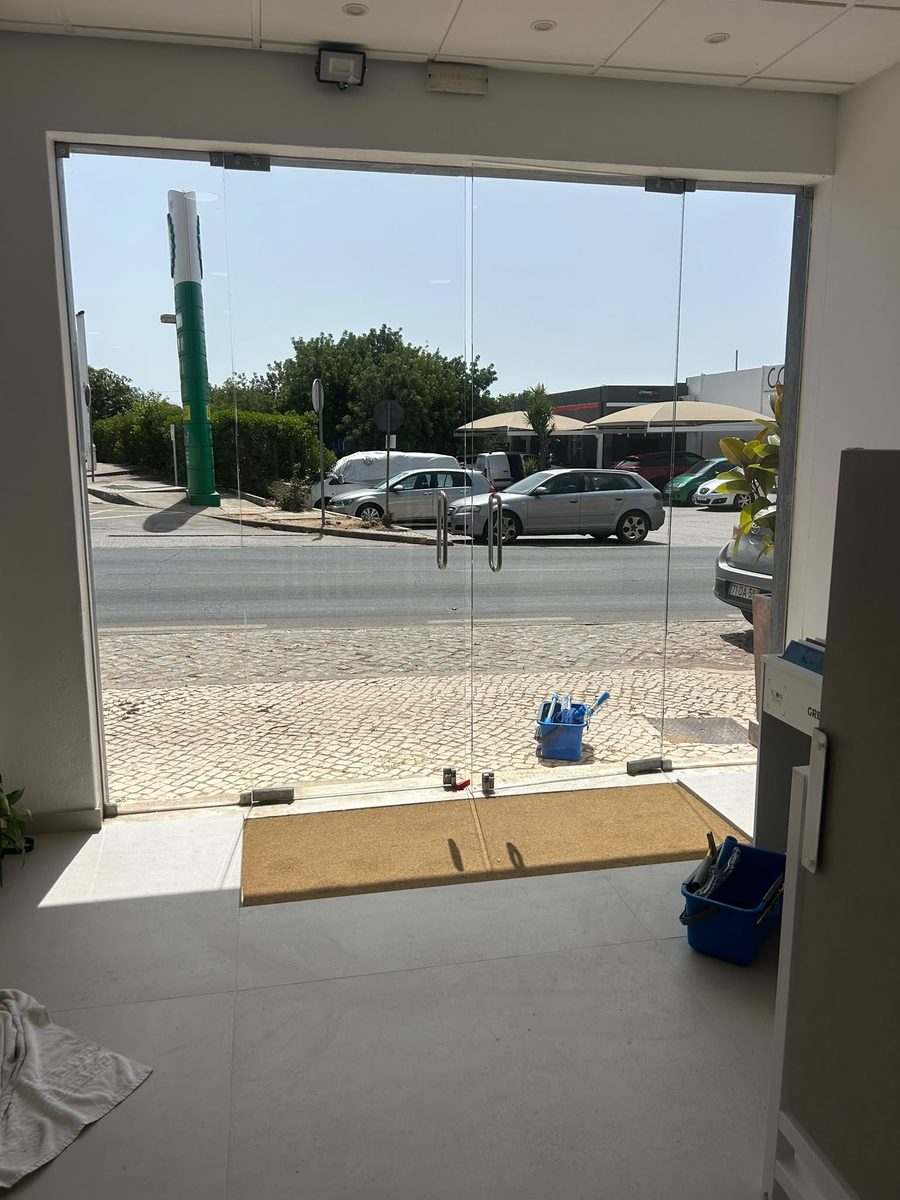 Cleaning the inside face of a showroom frontage in Almancil, with mat and bucket set down on the floor