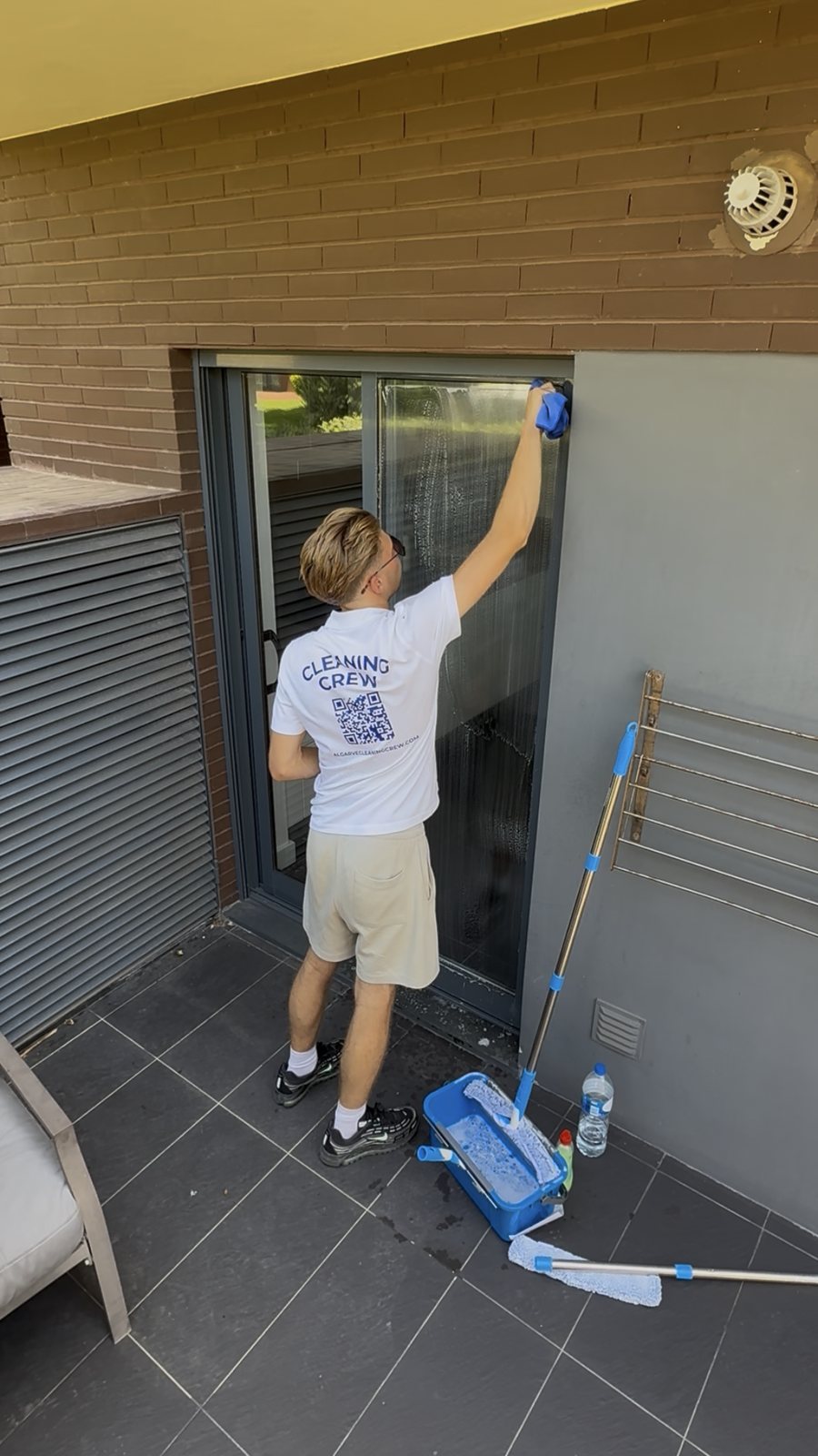 Using an extension pole to clean high sliding door glass at a Vilamoura apartment