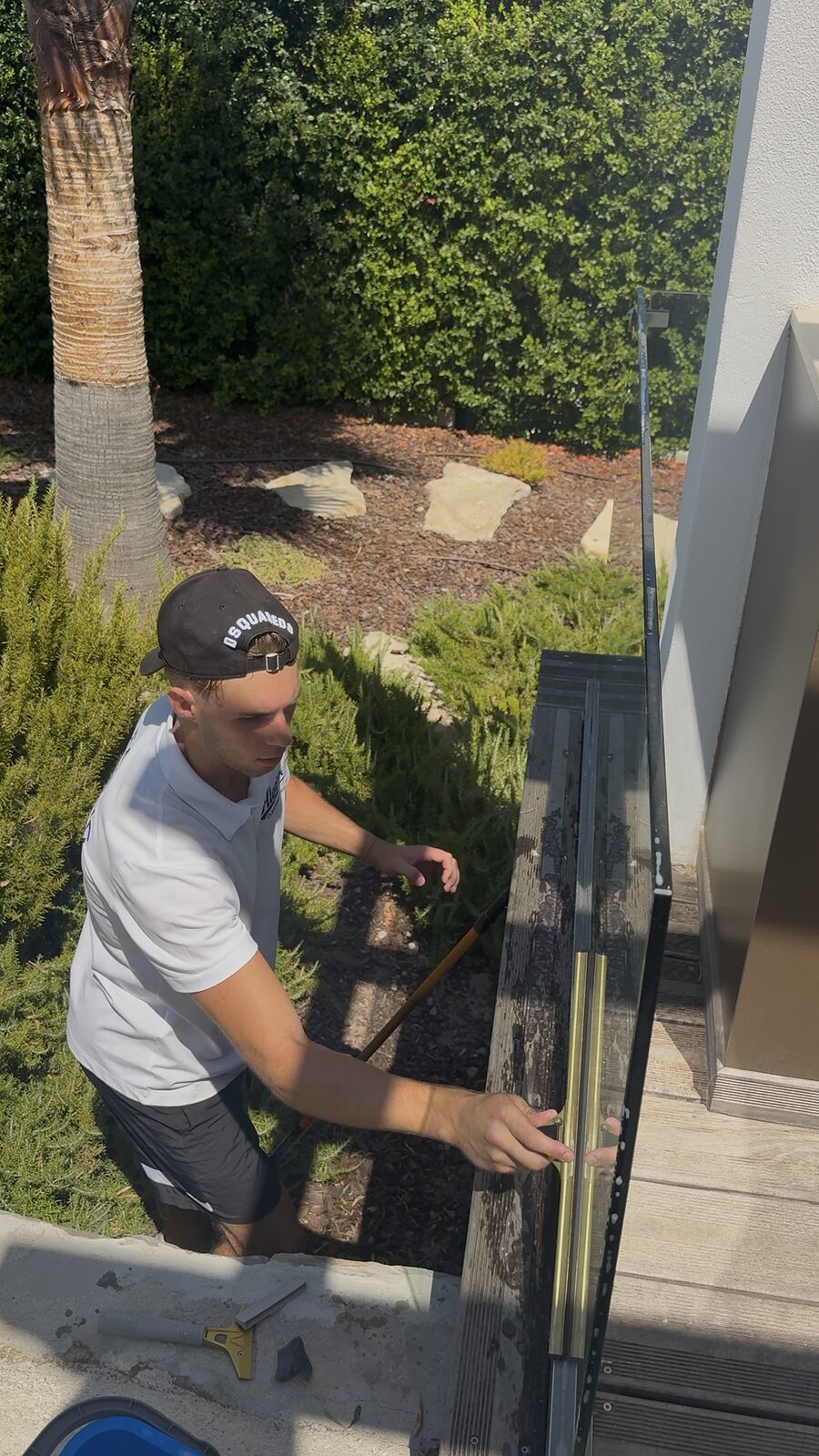 Cleaning a glass balcony panel from the terrace above at a Quinta do Lago villa