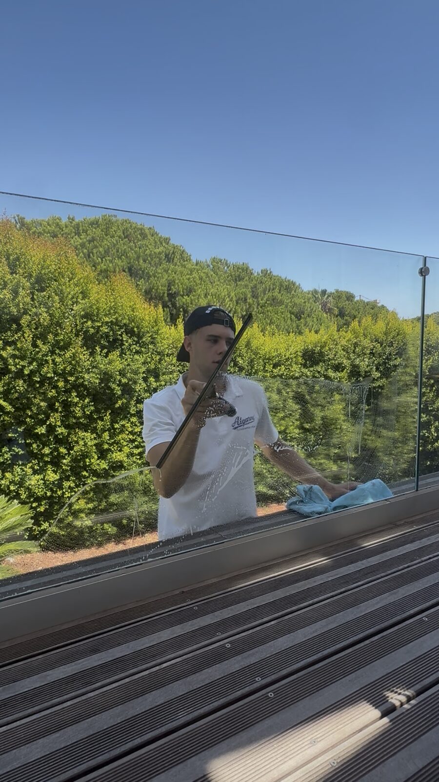 Squeegee pull on a glass balustrade panel overlooking the garden at a Quinta do Lago villa