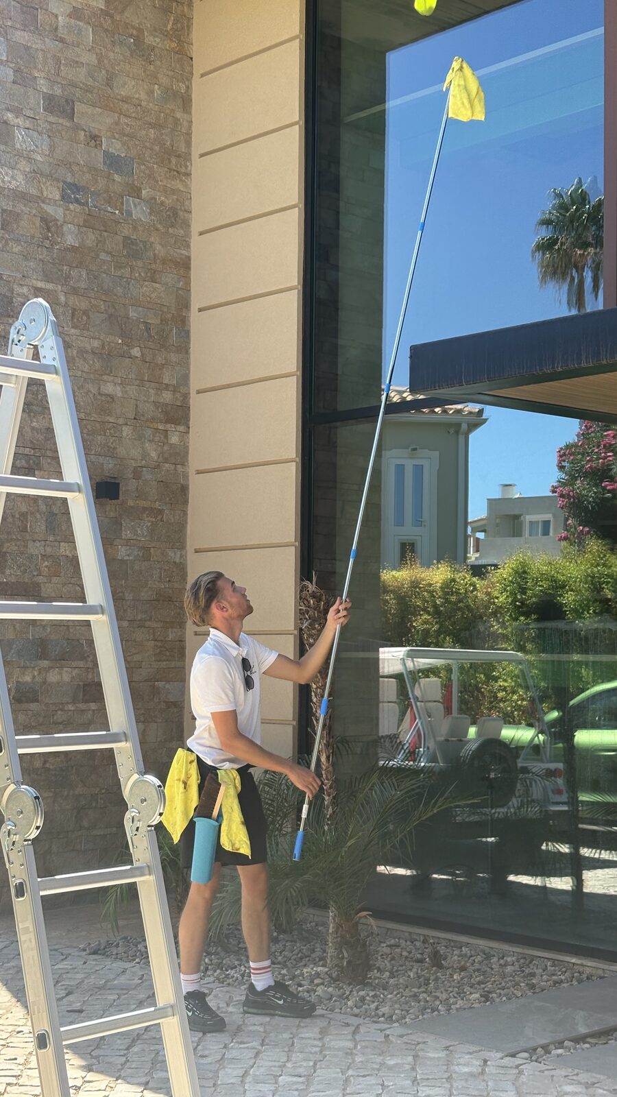 Ladder set on the drive and pole work on the upper glass at a villa in Vale Formoso