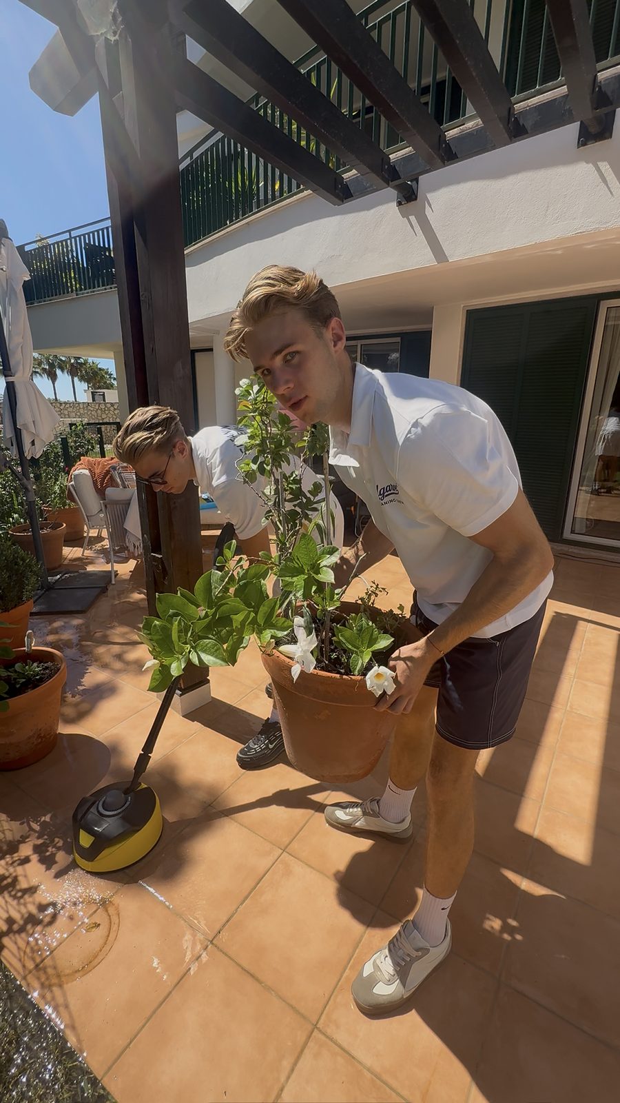 Moving a planter clear of the terrace before pressure washing at an apartment in Vilamoura