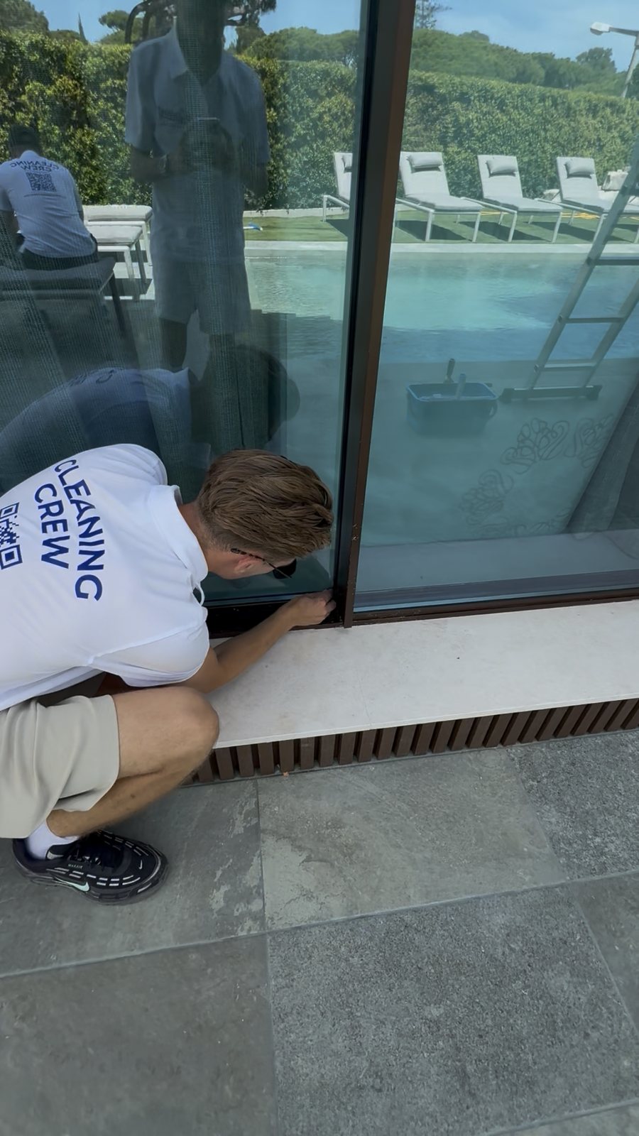 Cleaning the frame and track at the base of a full-height sliding door in Vale do Lobo