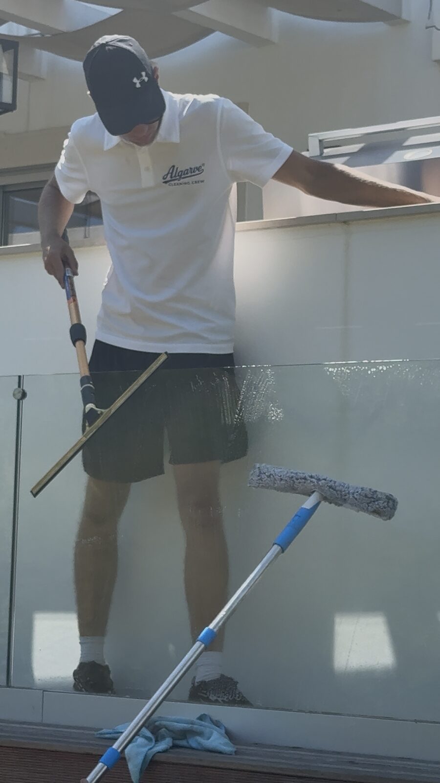 Washing down a glass balcony panel at a villa in Quinta do Lago