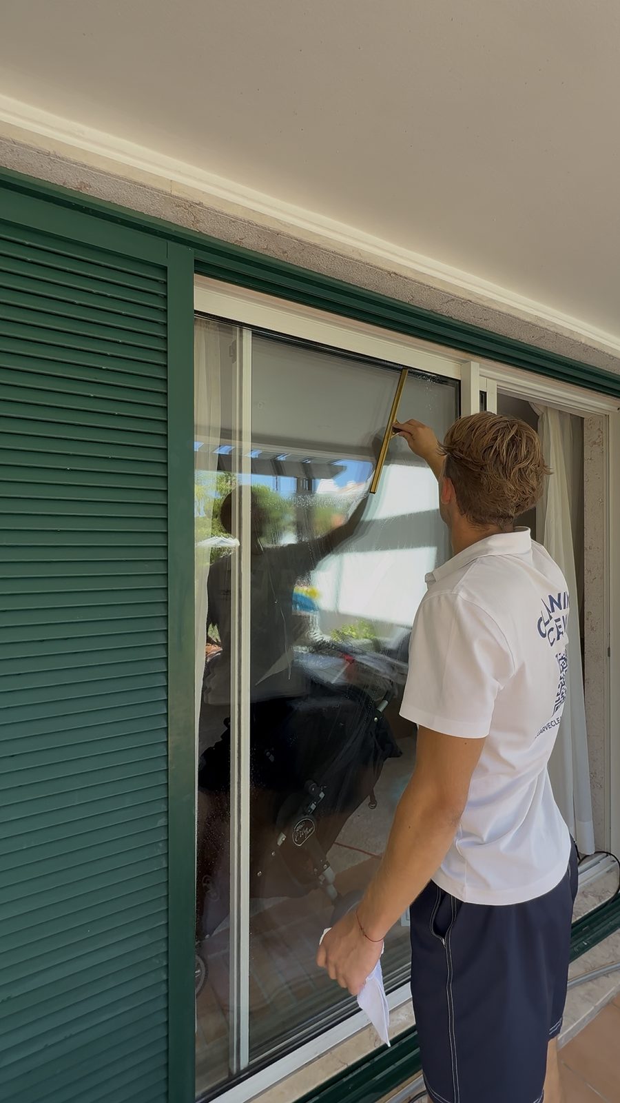 Squeegeeing the outside face of a patio door at an apartment in Vilamoura